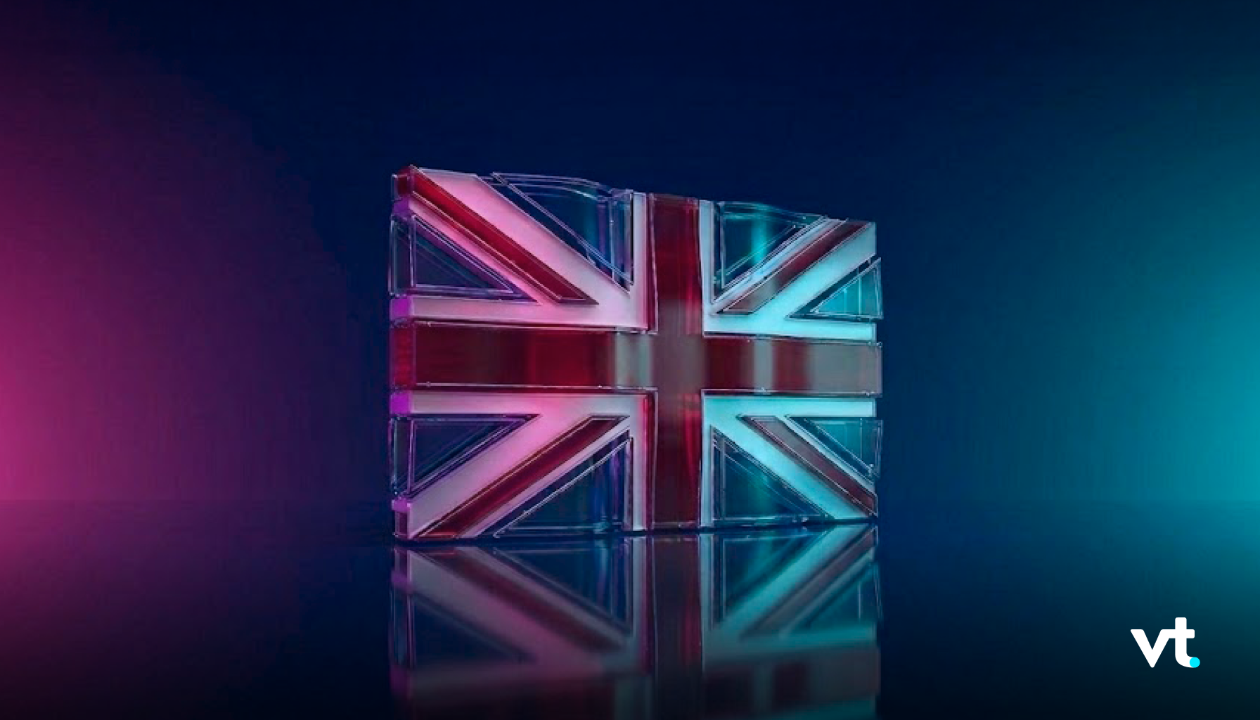 Glass block sculpture of the UK flag, illuminated in pink and teal with a reflective surface and VT logo in the bottom-right corner.