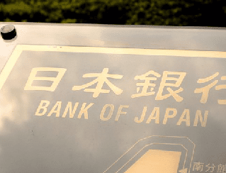 Close-up of a Bank of Japan sign with Japanese characters and the English text 'BANK OF JAPAN' on a reflective surface.