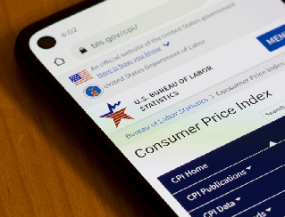 Smartphone on a wooden table displaying the U.S. Bureau of Labor Statistics Consumer Price Index page on its screen.