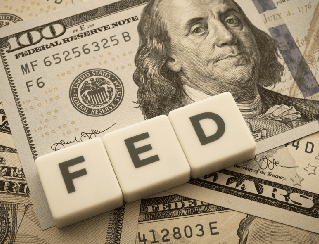 Block letters FED laid on top of scattered US $100 bills, implying Federal Reserve money.