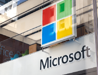 Microsoft storefront with the colorful four-square logo and the word Microsoft on glass panels.