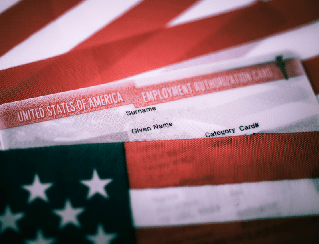 American flag draped over a stack of employment application forms in the background, suggesting patriotism and hiring context.