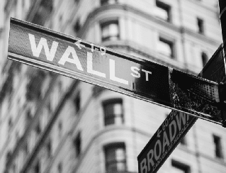 Intersection street signs for Wall Street and Broadway in New York City (black-and-white photo).