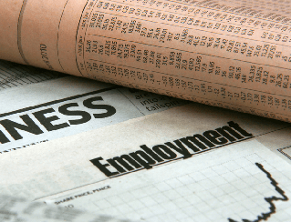 Rolled newspaper over a page labeled Employment and a business graph, suggesting job market or employment news.