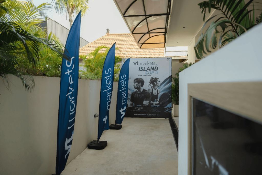 Outdoor corridor with blue vertical banners and a large event poster reading Island Cup 4 featuring athletes in the background
