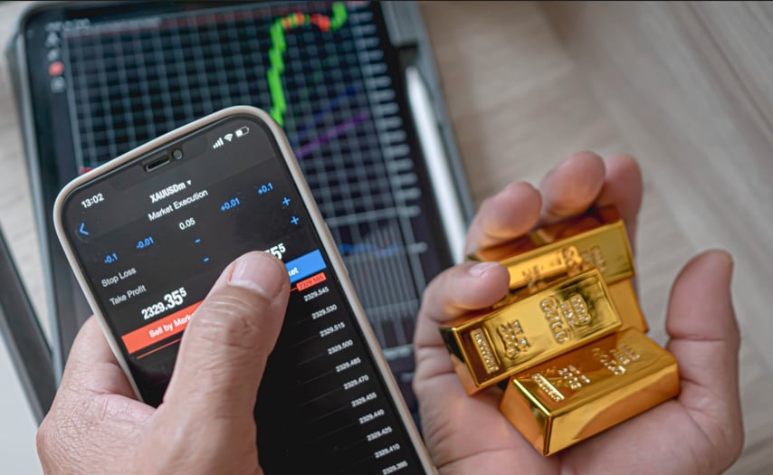 一位投資者一手握著金條、一手操作手機上的 XAUUSD 交易畫面，象徵使用 CFD 平台進行黃金交易時的靈活與實時決策能力，呼應文章主題「如何選擇合適的 CFD 平台」